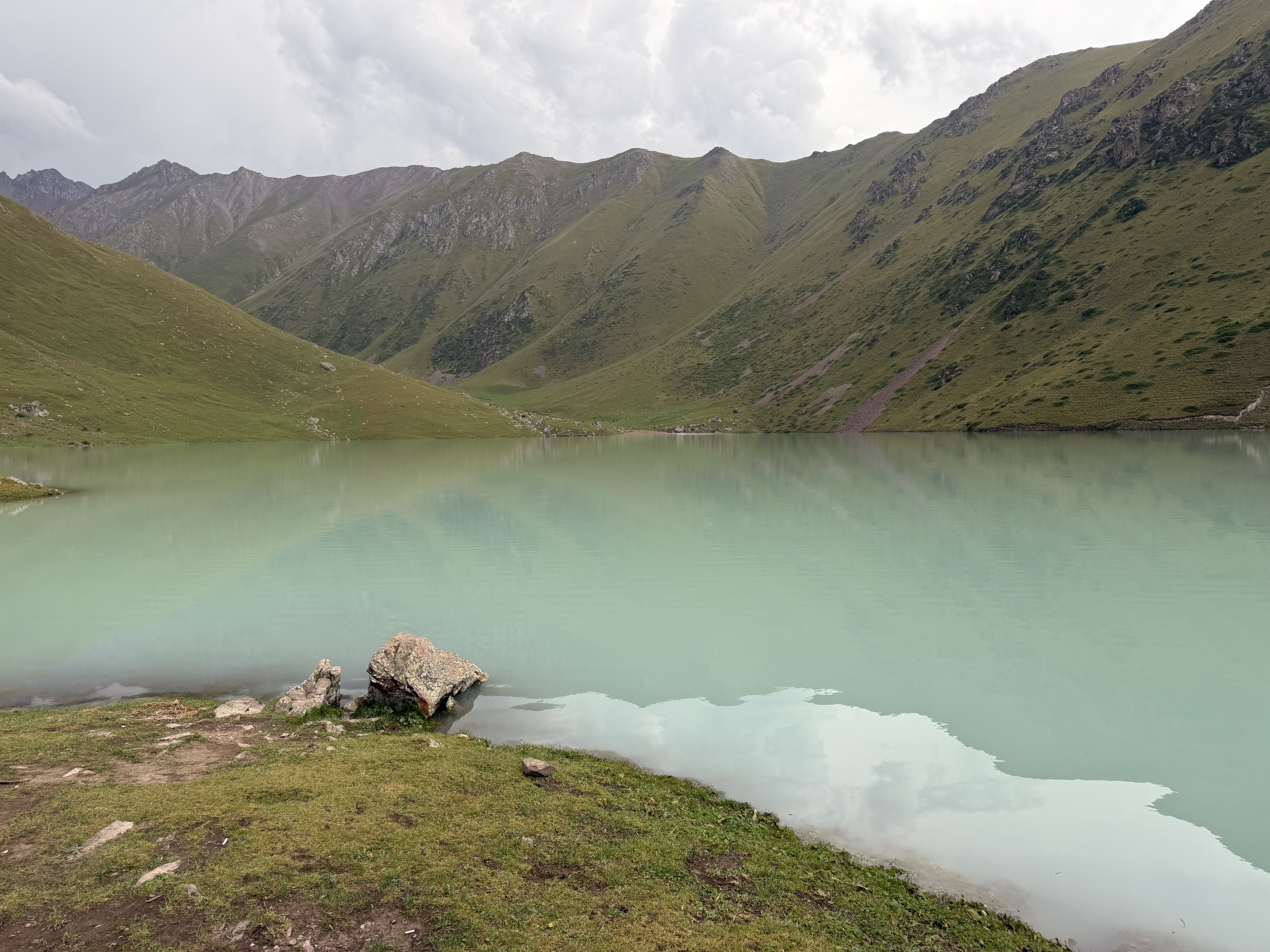 A turquoise lake surrounded by green mountains.